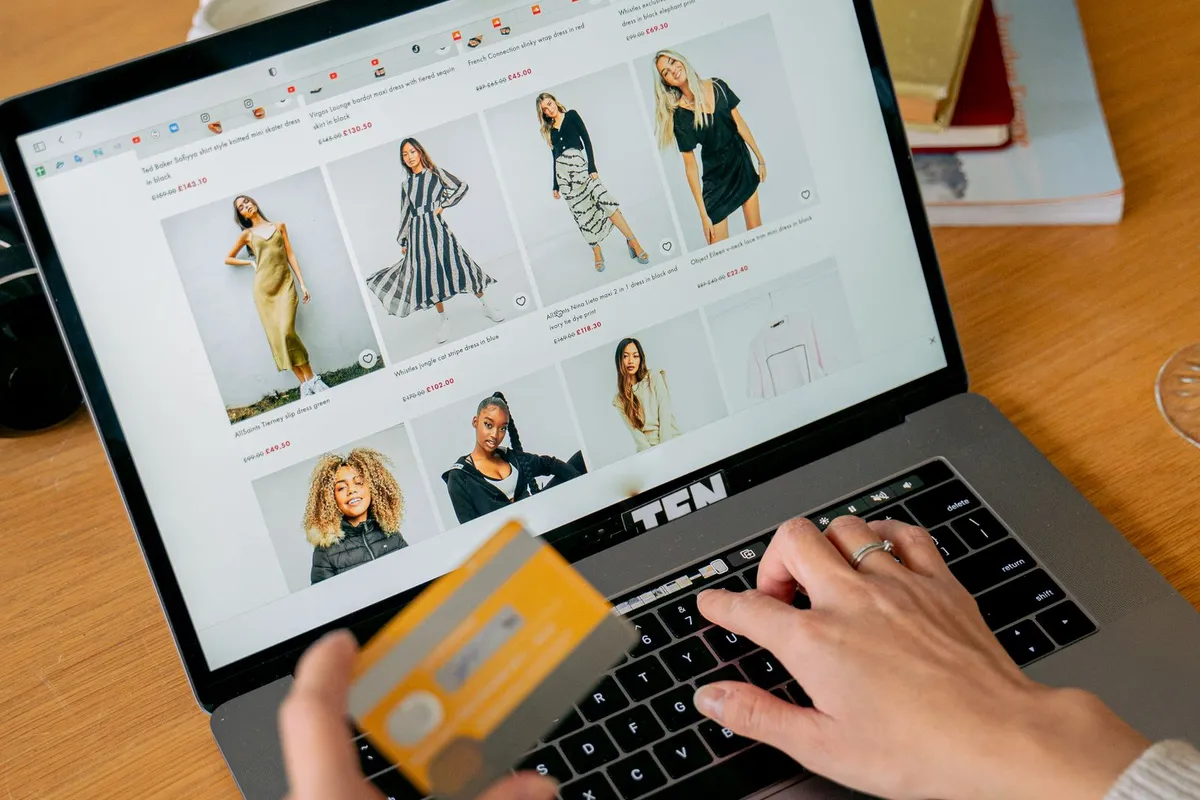 En person handler på nett med betalingskort foran en laptop.