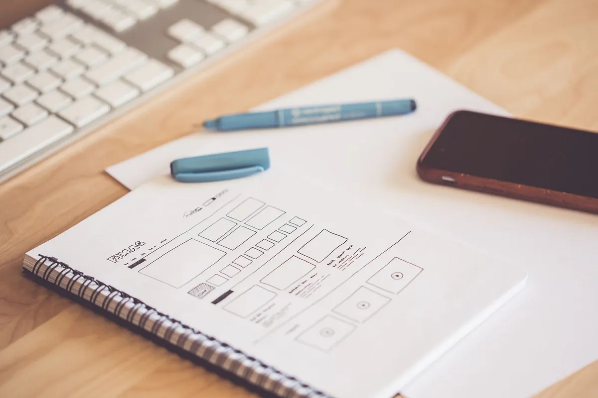 Wireframe-skisser av en nettside på papir på en arbeidspult.