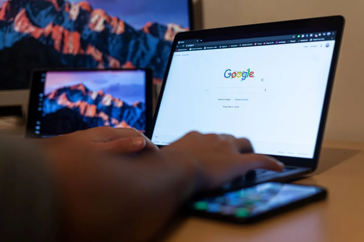 Hender som skriver på en laptop med Google-søk åpent.