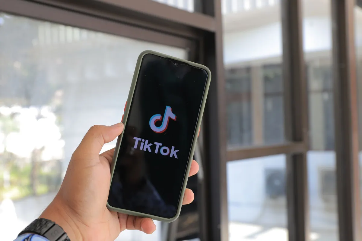 En hånd holder en mobil med TikTok-appen åpen.